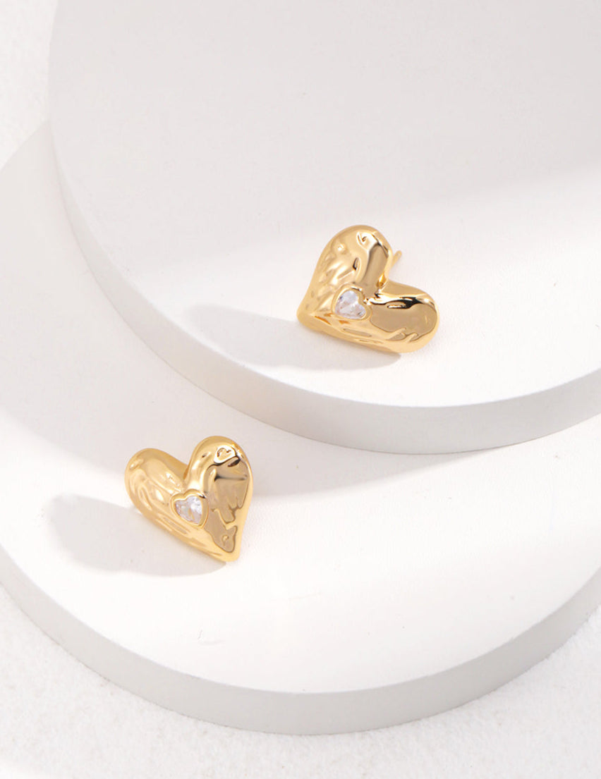 Gold heart-shaped earrings on a white surface