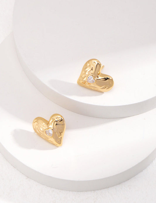 Gold heart-shaped earrings on a white surface