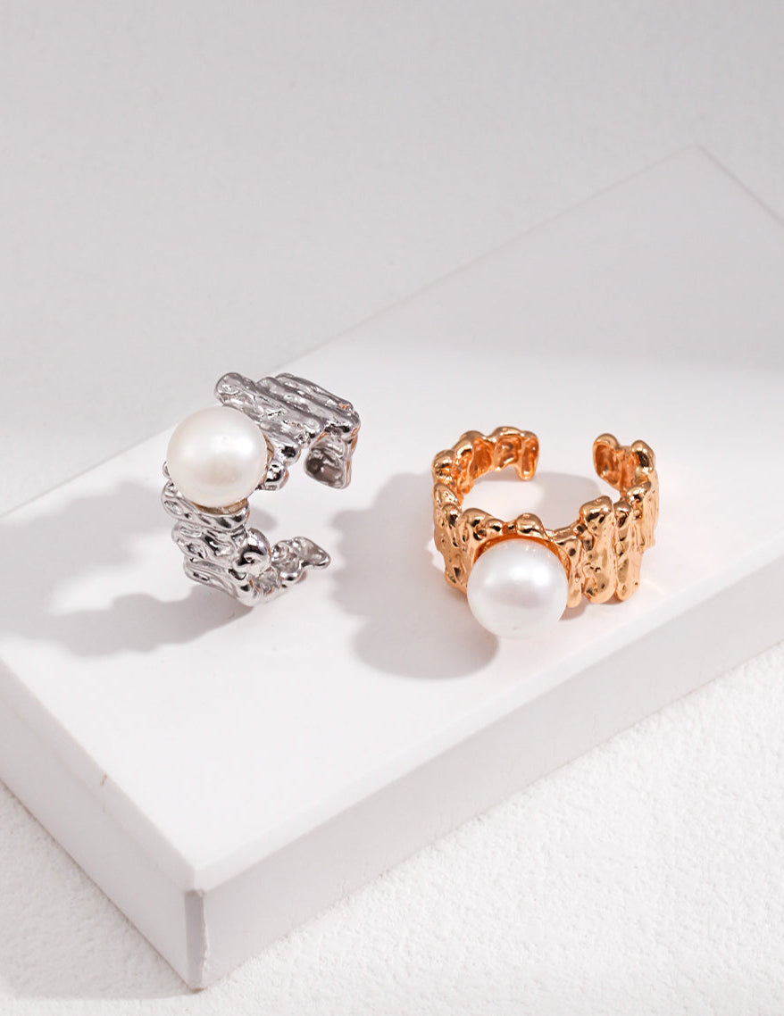 Two pearl-encrusted rings, one silver and one gold, on a white surface.