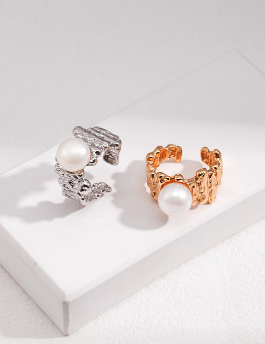 Two pearl-encrusted rings, one silver and one gold, on a white surface.
