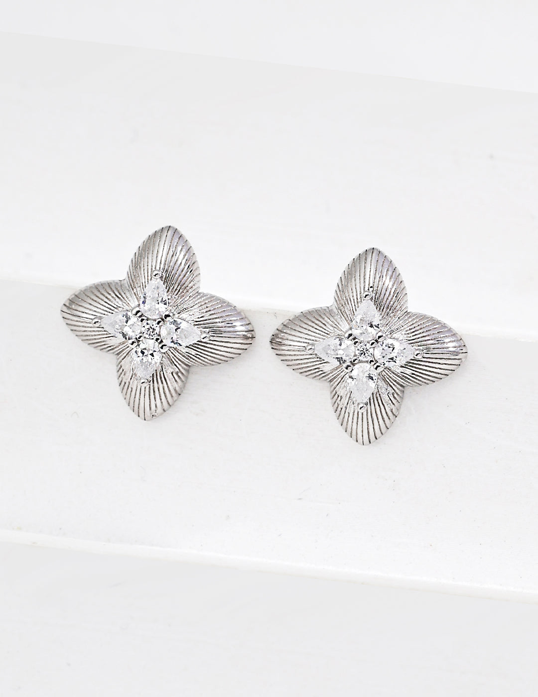 Pair of silver floral earrings with clear gemstones on a white background