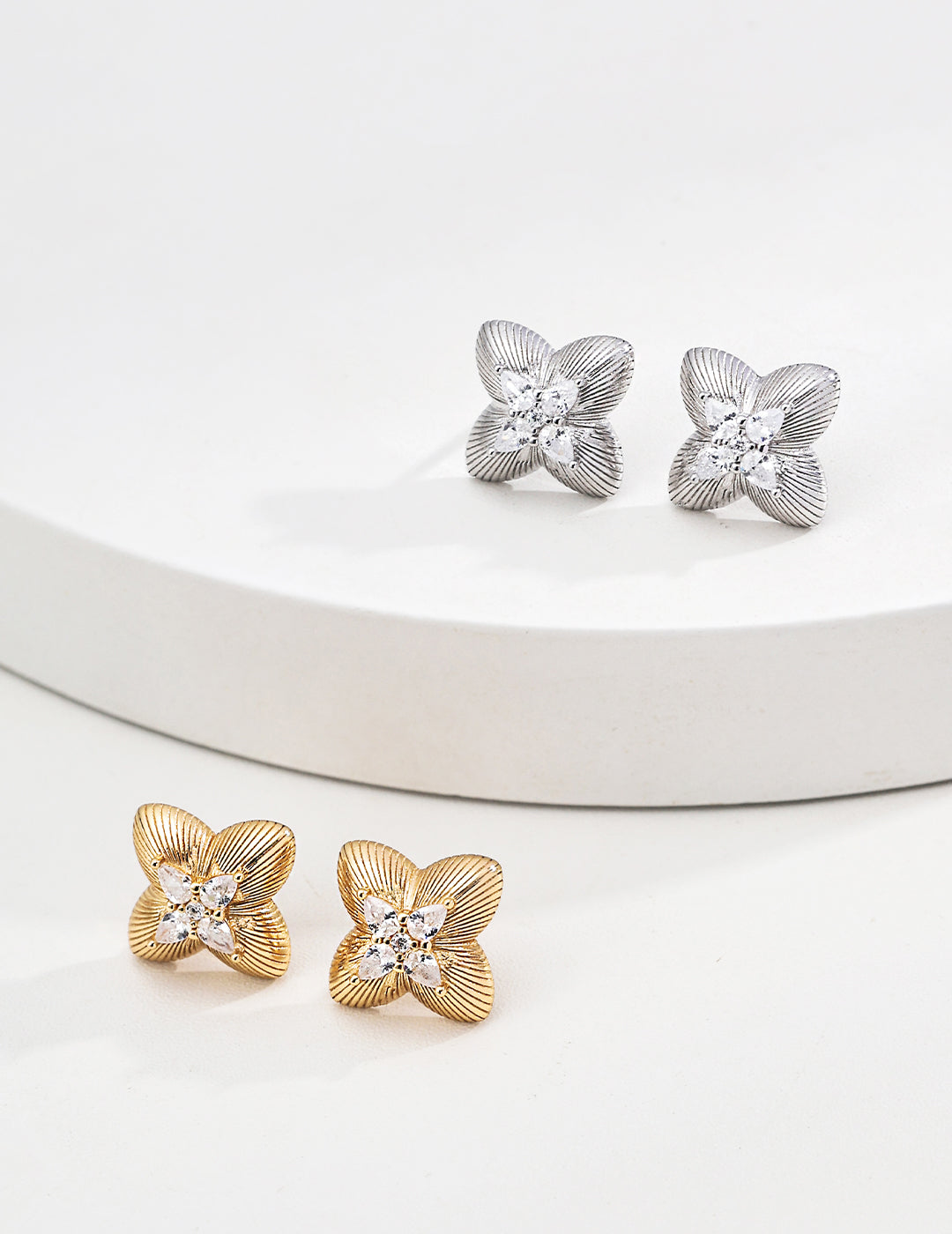 Pair of gold and silver floral earrings on a white surface
