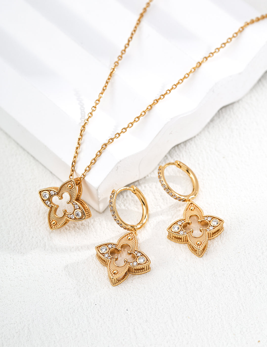 Gold jewelry set with necklace, earrings, and ring on a white background