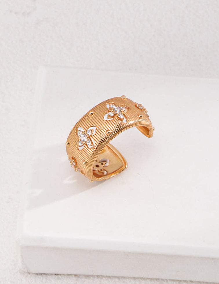 Gold bracelet with floral designs on a white surface