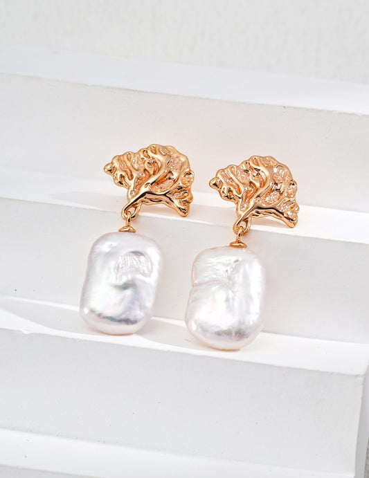 Gold earrings with baroque pearl drops on a white background
